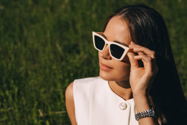 A young woman in sunglasses with a white frame on a summer green background