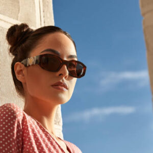 A portrait of a beautiful woman in sunglasses against blue sky.