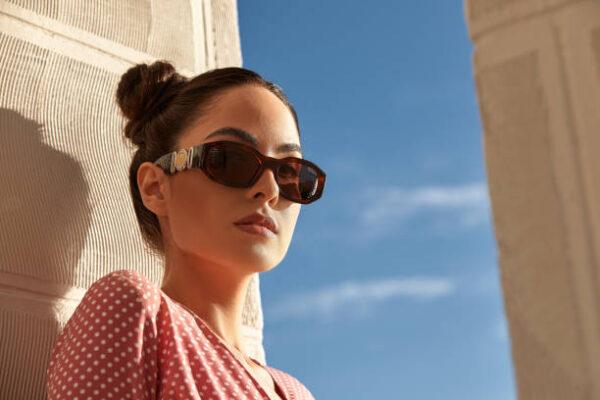 A portrait of a beautiful woman in sunglasses against blue sky.